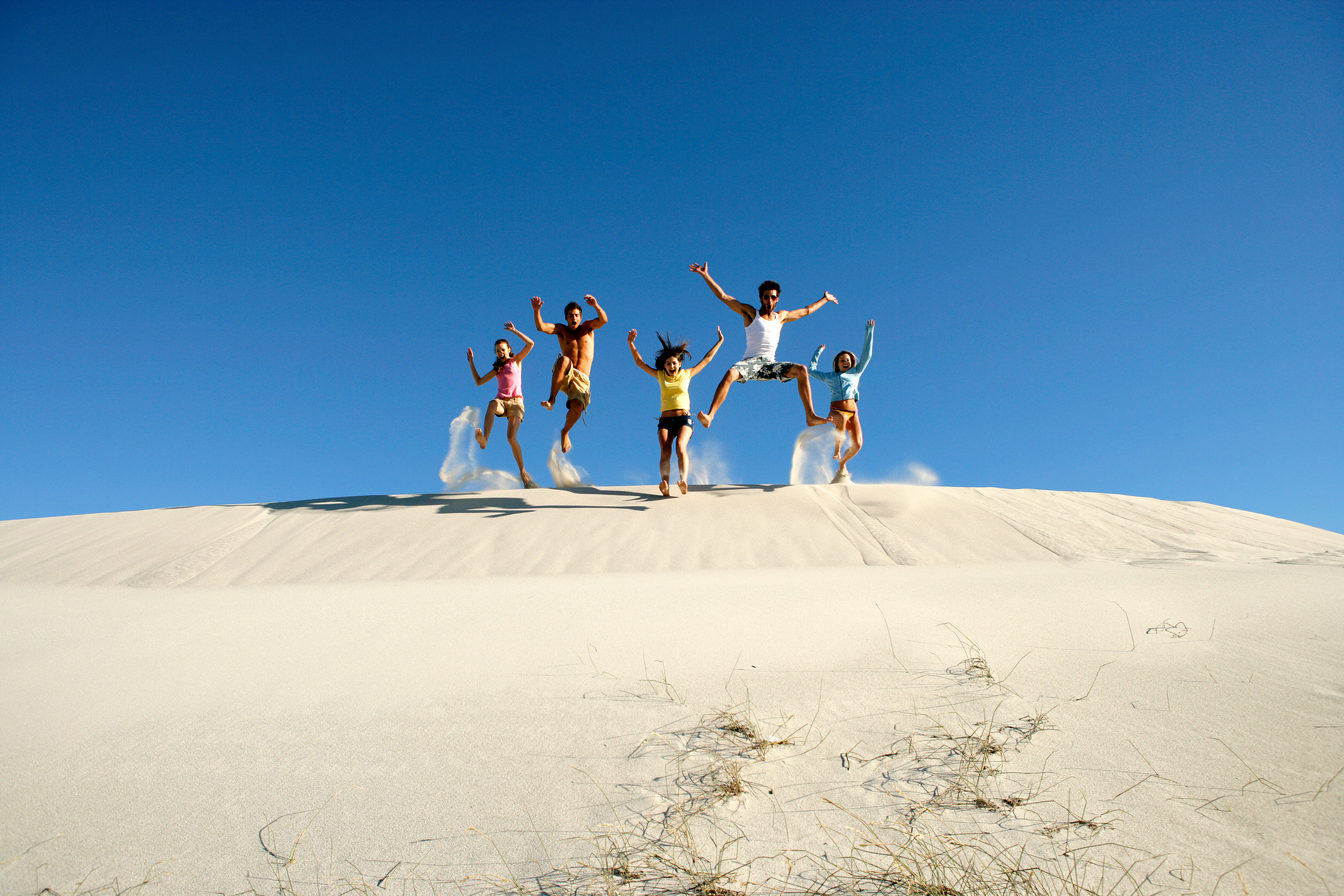 Group of people jumping in sand